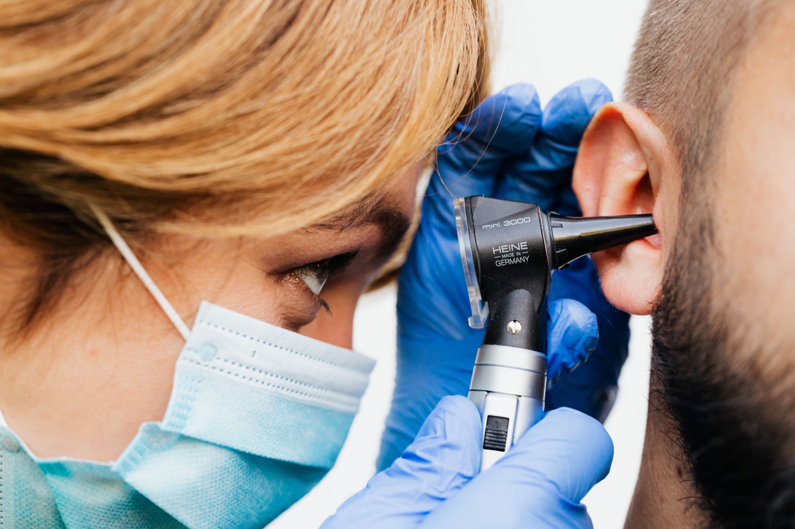 Audiologist performing otoscopic ear examination on a patient as part of a tinnitus assessment at Poorvam Hearing