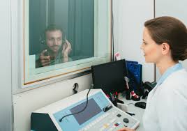 Audiologist performing pure tone audiometry hearing test in a sound-treated booth at Poorvam Hearing